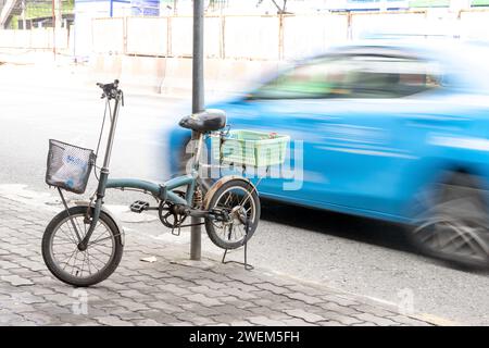 Le vélo garé sur une béquille sur le trottoir à côté d'une route très fréquentée, Bangkok, Thaïlande Banque D'Images