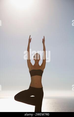 Jeune femme pratiquant le yoga avec l'océan dans l'arrière-plan Banque D'Images