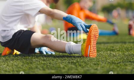 Young Boy Doing Soccer Stretching Exercises. Enfants participant à l'entraînement des gardiens de but de football. Groupe de garçons d'école dans la pratique de gardien de but de football pendant l'heure d'été. Banque D'Images