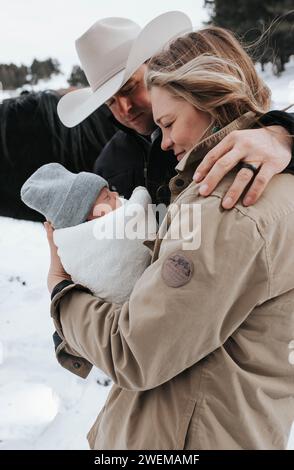 Maman et papa dans le stand de chapeau de cow-boy avec des chevaux, câlin bébé garçon Banque D'Images