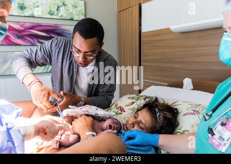 Papa afro-américain coupe le cordon ombilical du nouveau-né après la naissance Banque D'Images