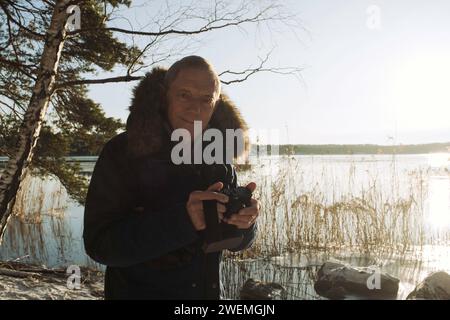 Portrait d'un homme prenant des photos d'un lac dans la neige en Suède Banque D'Images