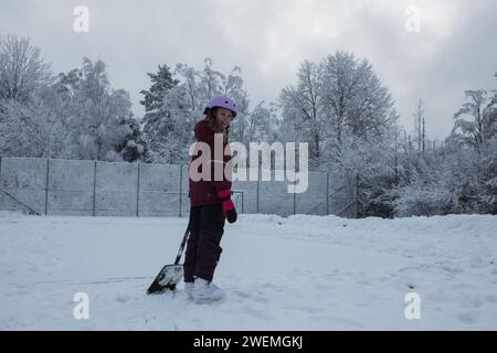 fille avec une pelle à neige patinant à l'extérieur Banque D'Images