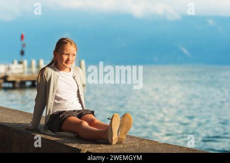 Mignonne petite fille reposant au bord du lac Genève au coucher du soleil Banque D'Images