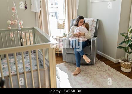 Mère berce bébé dans la crèche Banque D'Images