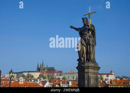 Statue de St. Jean-Baptiste sur le pont Charles, avec le château de Hradcany et St. Cathédrale de Vitus en arrière-plan, à Prague, République tchèque, sous le soleil Banque D'Images