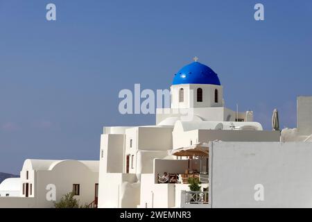 Maisons blanches dans l'architecture typique des Cyclades, au-dessus d'une église grecque avec dôme, Oia, IA, Santorin, Cyclades, Grèce Banque D'Images