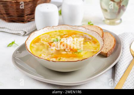 Soupe de poulet frais avec légumes et pâtes stelline dans un bol avec carotte et persil. Banque D'Images