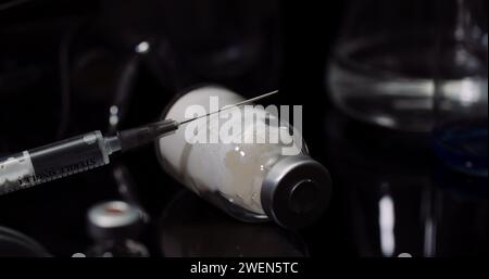 Equipement de laboratoire : seringue et médecine, tubes à essai et flacons tournant sur fond noir. Banque D'Images