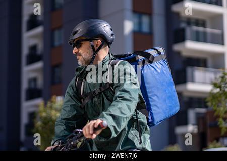 livreur chevauchant le vélo électrique dans la ville Banque D'Images