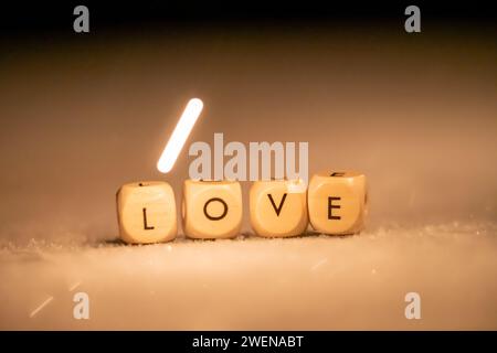 Cubes en bois avec les lettres AMOUR sur une surface givrée avec un boulon de lumière qui brille sur le mot Banque D'Images