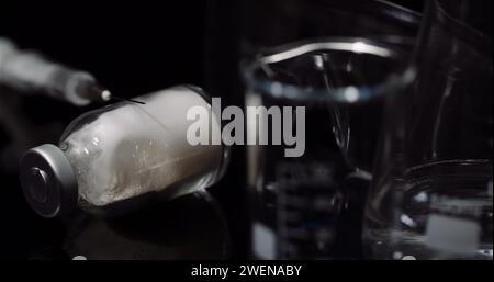 Equipement de laboratoire : seringue et médecine, tubes à essai et flacons tournant sur fond noir. Banque D'Images