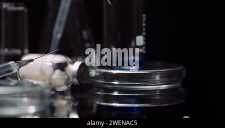 Equipement de laboratoire : seringue et médecine, tubes à essai et flacons tournant sur fond noir. Banque D'Images