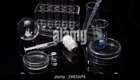 Equipement de laboratoire : seringue et médecine, tubes à essai et flacons tournant sur fond noir. Banque D'Images
