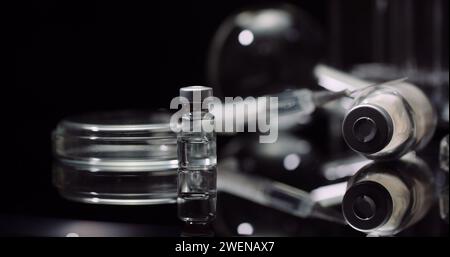 Equipement de laboratoire : seringue et médecine, tubes à essai et flacons tournant sur fond noir. Banque D'Images