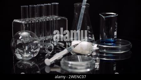 Equipement de laboratoire : seringue et médecine, tubes à essai et flacons tournant sur fond noir. Banque D'Images