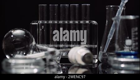 Equipement de laboratoire : seringue et médecine, tubes à essai et flacons tournant sur fond noir. Banque D'Images