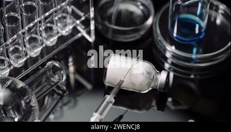 Equipement de laboratoire : seringue et médecine, tubes à essai et flacons tournant sur fond noir. Banque D'Images