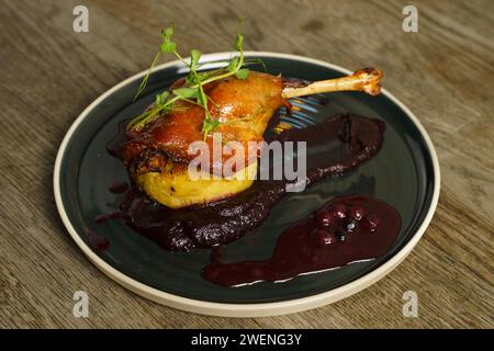 Cuisse de canard rôtie sur purée de pommes de terre avec oignon, crème de chou violet et jus de myrtille Banque D'Images