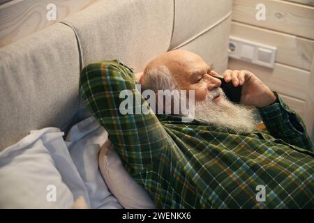 Vieil homme s'allongea pour se reposer sur un lit confortable à la maison Banque D'Images