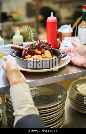 Le personnel du restaurant sert de la viande garnie d'une branche de thym Banque D'Images