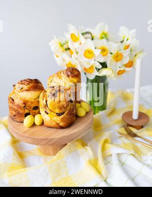 Pâtisseries fraîchement cuites, bonbons jaunes et jonquilles blanches sur un tissu à carreaux. Une belle table printanière. Concept de vacances de Pâques Banque D'Images