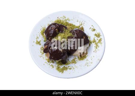 Délicieuses profiteroles au chocolat et assiette blanche, isolées. Banque D'Images