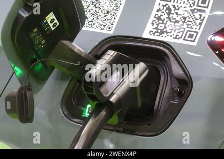 Erfurt, Allemagne. 26 janvier 2024. Un câble de recharge est branché sur la prise d’une voiture électrique du stand Thüringer Energiewerke dans un hall d’exposition de l’Automobil Messe Erfurt. Au total, 130 exposants présentent les derniers développements du marché automobile dans trois halls d'exposition. Crédit : Bodo Schackow/dpa/Alamy Live News Banque D'Images