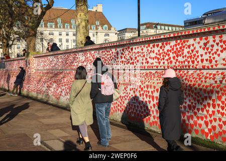 Londres, Royaume-Uni. 26 janvier 2024. Vue générale du mur avec passants. Les bénévoles du mur commémoratif national du Covid préservent certains des plus de 200 000 cœurs, chacun représentant quelqu’un qui est mort du Covid. Les volontaires, également issus de familles endeuillées, repeignent minutieusement les cœurs rouges, puis retracent les messages sur eux. Ils se battent également actuellement pour préserver le mur en tant que mémorial et exhortent le gouvernement à agir sur les recommandations faites par la Commission britannique pour la commémoration du Covid, présidée par la baronne Morgan, à le faire. Crédit : Imageplotter/Alamy Live News Banque D'Images