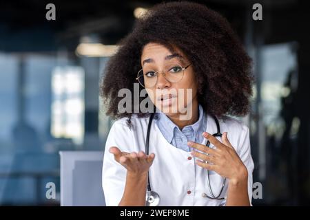Vue à la première personne d'une infirmière qui parle et fait des gestes avec les mains tout en ayant un appel vidéo. Femme médicale afro-américaine parlant sur la conférence en ligne et partageant son expérience avec des collègues. Banque D'Images