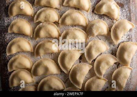Boulettes crues varenik - cuisine ukrainienne traditionnelle - sur une planche de bois en gros plan. Photographie culinaire Banque D'Images