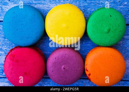 TopShot de macarons français doux et colorés sur fond en bois bleu Banque D'Images