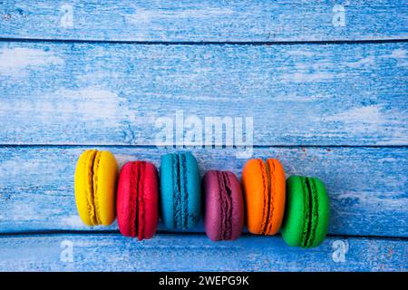 TopShot de macarons français doux et colorés sur fond en bois bleu. Banque D'Images