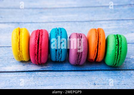 TopShot de macarons français doux et colorés sur fond en bois bleu. Banque D'Images