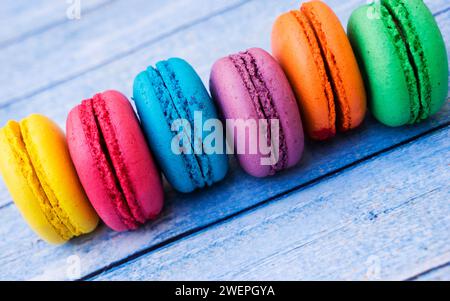 TopShot de macarons français doux et colorés sur fond en bois bleu. Banque D'Images