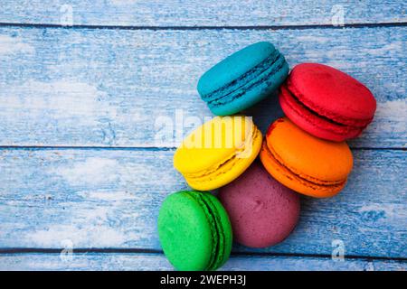 TopShot de macarons français doux et colorés sur fond en bois bleu. Banque D'Images