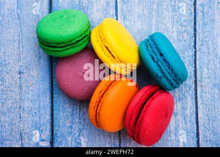 TopShot de macarons français doux et colorés sur fond en bois bleu Banque D'Images