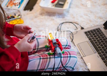 Tallinn, Estonie - 25 décembre 2023 : enfant construisant un robot Lego Education WEDO en mouvement à la maison. Banque D'Images