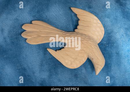 Grand oiseau sculpté de figure de colombe sur le tissu bleu semble descendre en vol. Les ailes sont déployées comme si elles venaient chercher la paix et l'amour. Banque D'Images