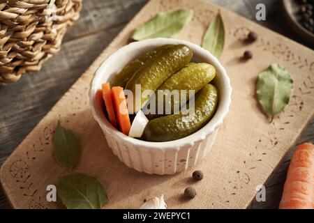 Cornichons ou cornichons de concombre faits maison dans un bol blanc sur une table Banque D'Images