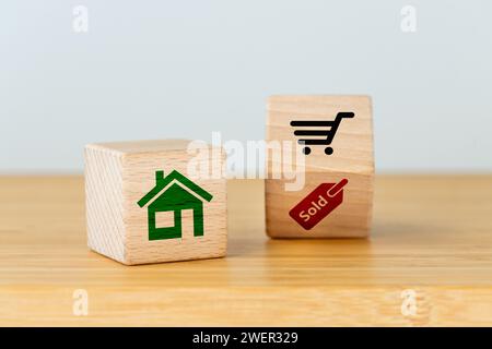 Achat d'une maison ou d'un appartement, symbole d'achat immobilier, concept de logement, blocs en bois avec maison, panier et icônes vendues mot Banque D'Images