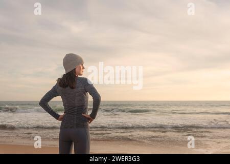 coureur femme sportive, se reposant et regardant la mer après avoir couru à la plage Banque D'Images