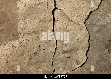 Fissure dans le revêtement en béton d'une vieille maison. Surface rugueuse et irrégulière. Plâtre de ciment sur un mur de briques, texture, fond. Toile de fond en ciment antique Banque D'Images