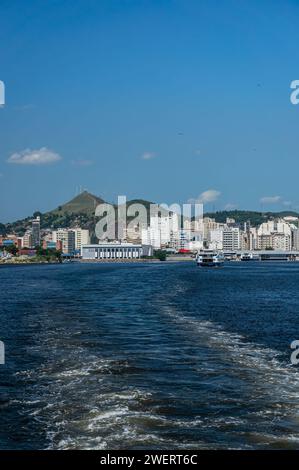 Vue partielle et lointaine de la côte du district Centro de Niteroi comme vu des eaux bleues de la baie de Guanabara sous l'après-midi d'été ensoleillé ciel bleu clair. Banque D'Images