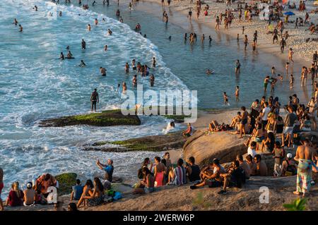 Beaucoup de gens se rassemblent sur les environs de la péninsule rocheuse Arpoador à la plage Arpoador pour regarder le soleil se coucher sur les eaux de l'océan Atlantique. Banque D'Images