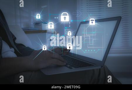 Protection de la vie privée. Homme utilisant un ordinateur portable à la maison, gros plan. Schéma numérique avec cadenas près de l'appareil Banque D'Images