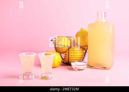 Coups et bouteille de savoureux Limoncello sur fond rose Banque D'Images