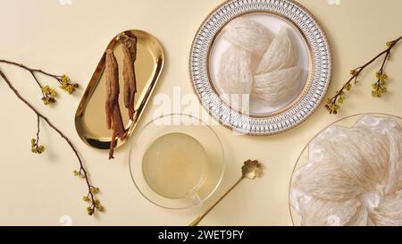 Vue de dessus du nid d'oiseau, soupe de bol et ginseng rouge sur fond beige. Nourriture et herbe de la nature, rare, populaire en Chine et en Corée. Santé. Banque D'Images