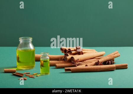 Vue de face de bouteilles en verre sans étiquette, contenant des huiles essentielles, bâtonnets de cannelle et anis sur fond bleu. Scène de maquette pour produit de cinnam Banque D'Images
