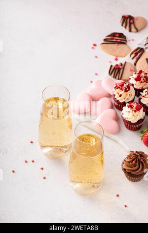 Champagne pour la Saint Valentin avec planche de charcuterie dessert avec cupcakes, biscuits, baies fraîches et chocolats Banque D'Images